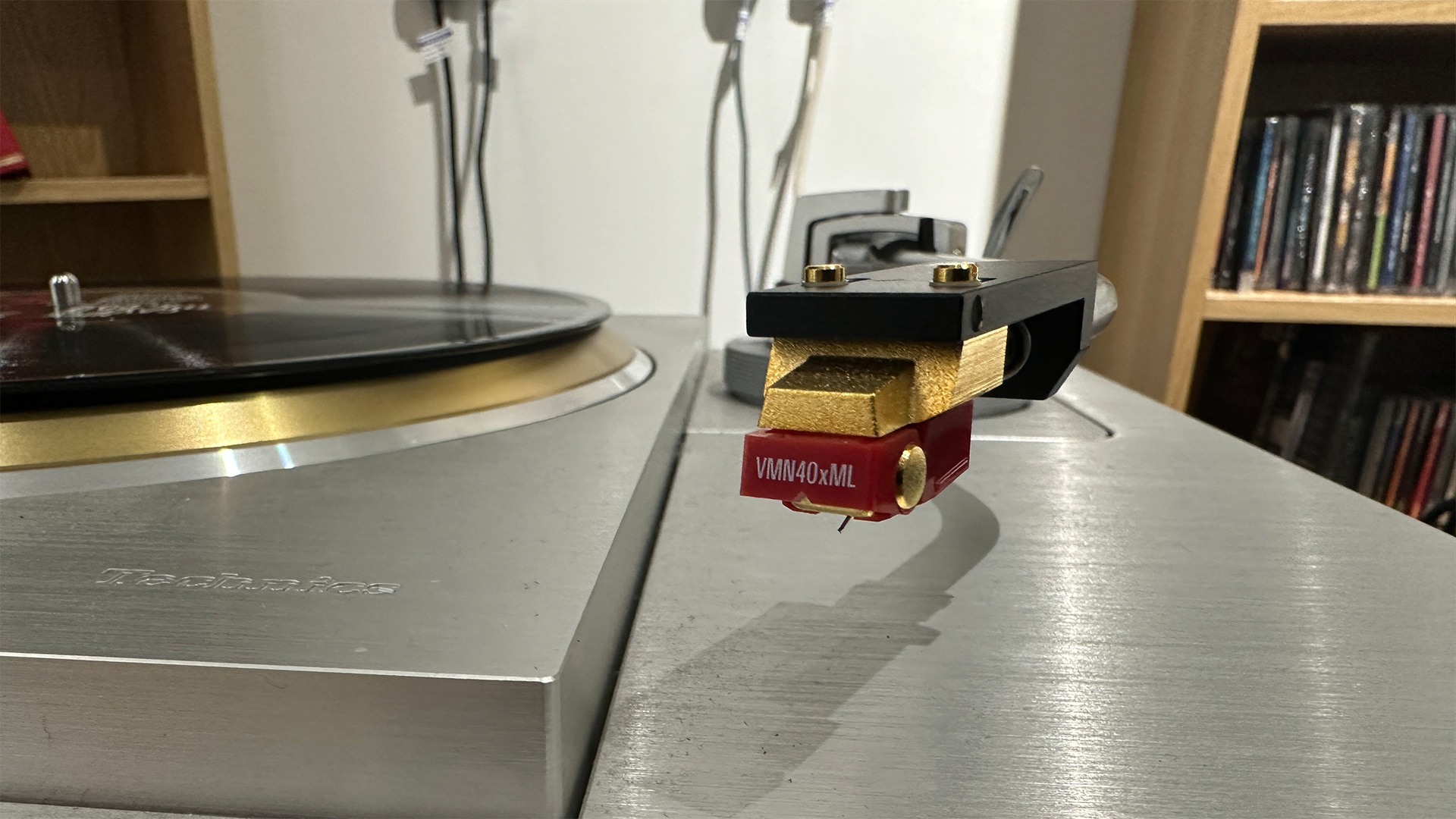 Audio-Technica AT-VM740xML moving magnet cartridge on Technics tonearm next to turntable with black vinyl on platter