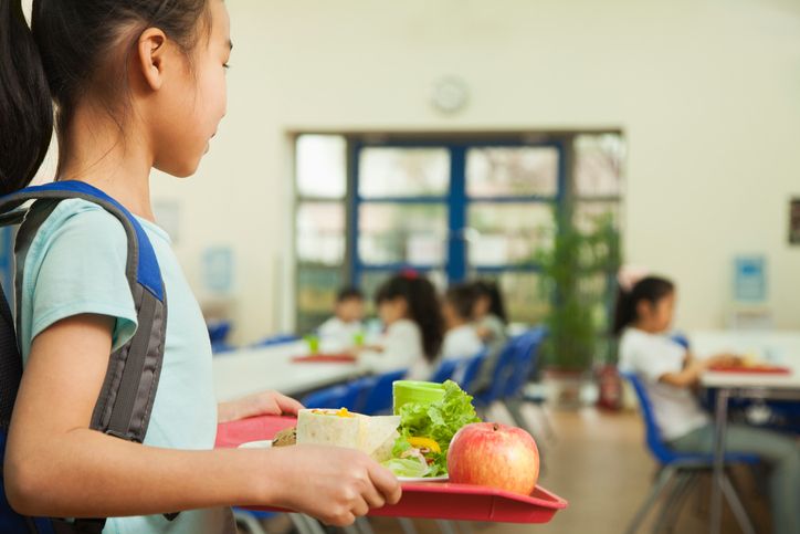 A girl holds a tray of food.