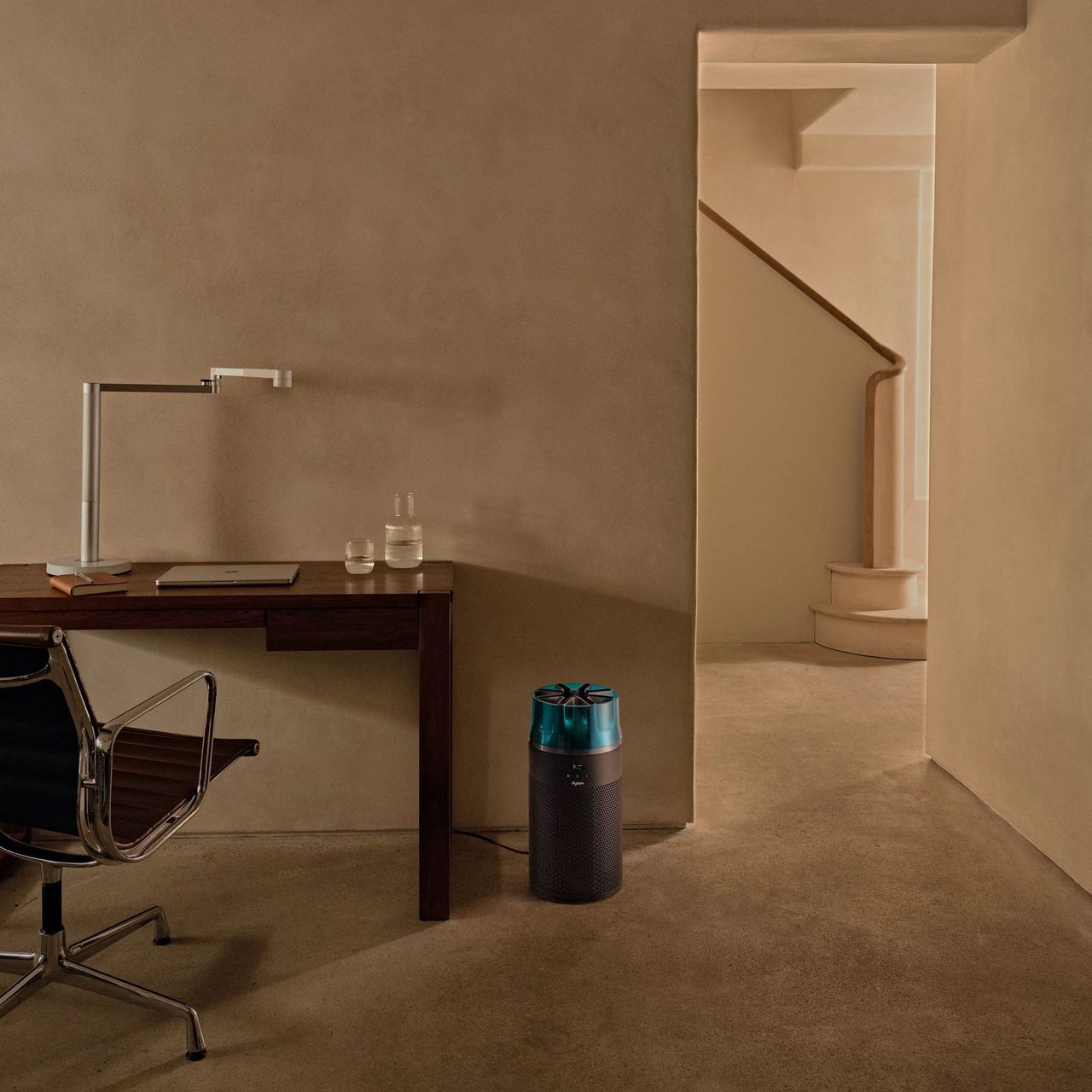 Dyson HushJet Air Purifier in a concrete-style office, sitting on the floor next to a desk and desk chair