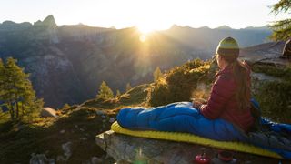 best 2-season sleeping bags: camper enjoying the sunset from sleeping bag
