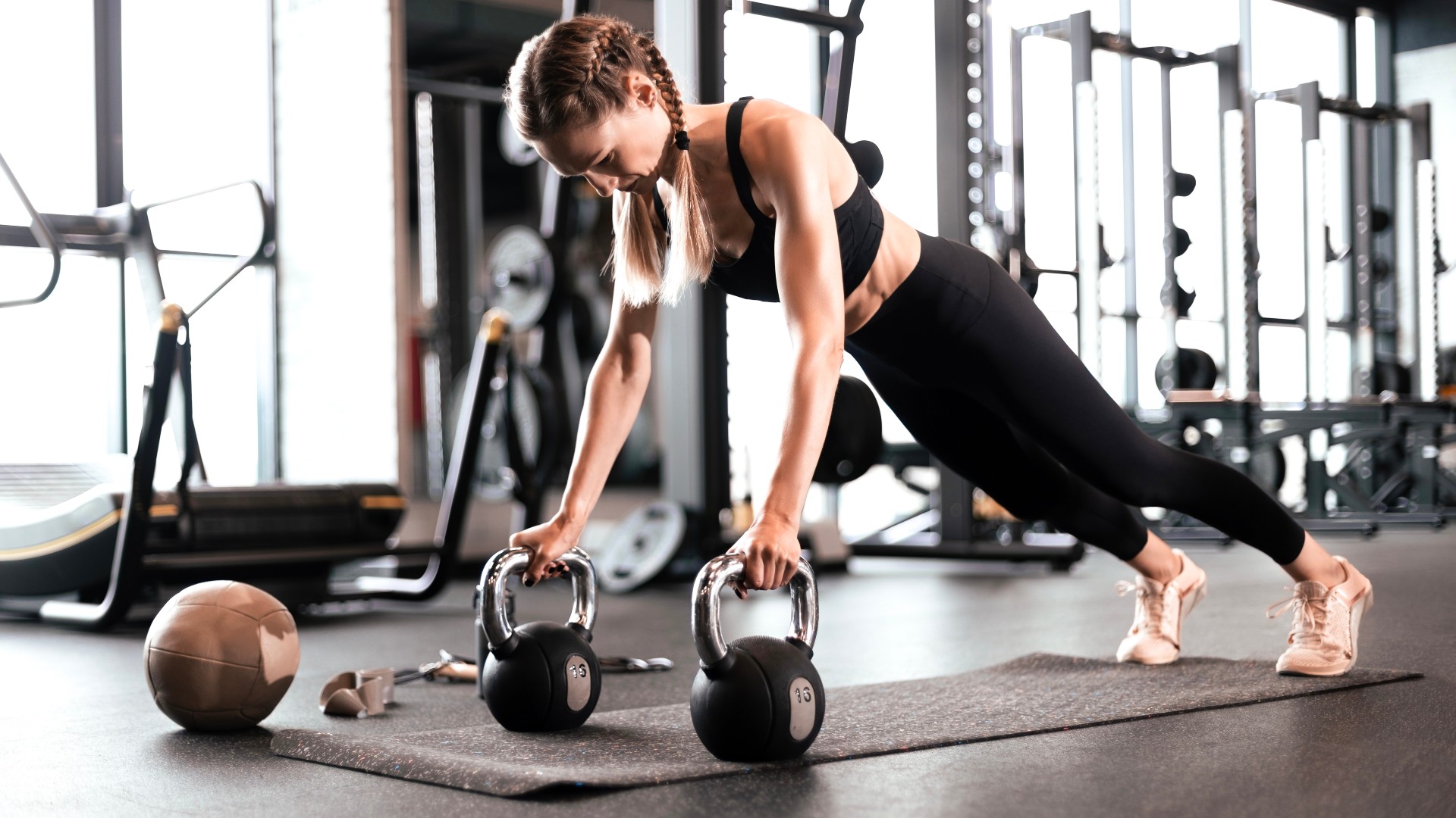 Woman performing rebellious row using two kettlebells