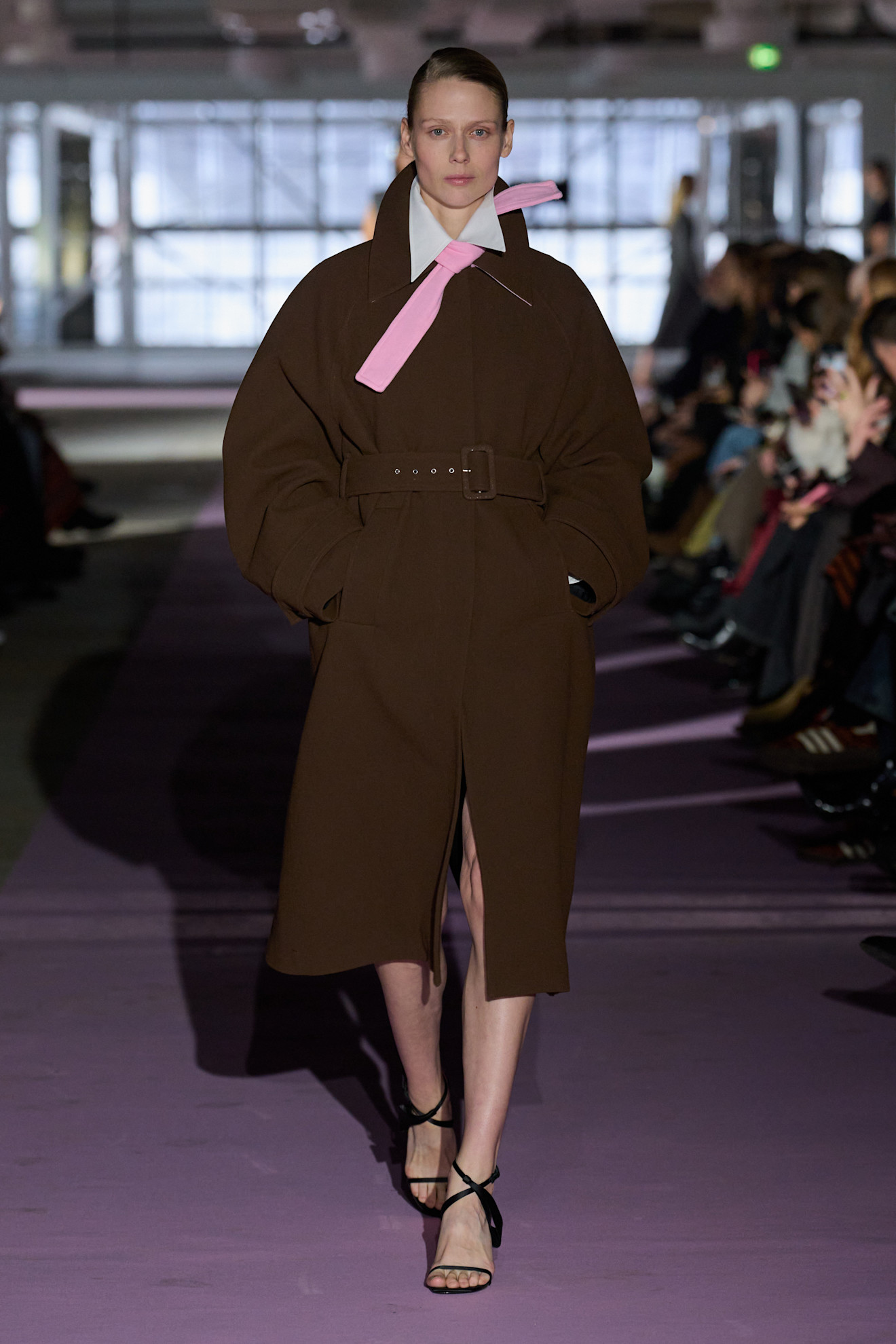 a model at Forza Collective Fall 2026 wearing a brown coat, white shirt, and pink wind-blown necktie
