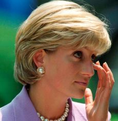 Princess Diana wearing a purple suit and rubbing her eye