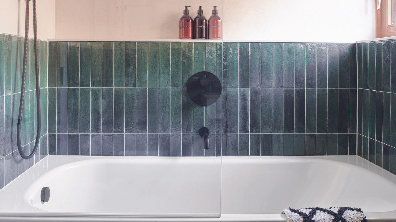 Bathroom with dark green subway tiles on top of a bath.