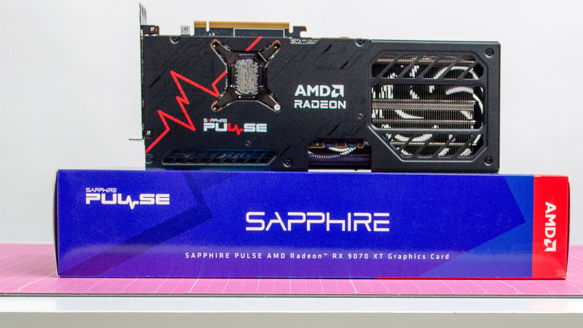 An AMD Radeon RX 9070 XT made by Sapphire on a table with its retail packaging