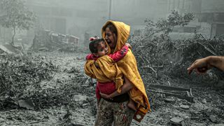 A woman holds a girl as Israeli air strikes hit Gaza City
