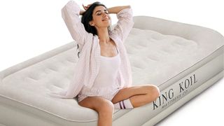 A woman sits cross legged on a beige King Koil air mattress