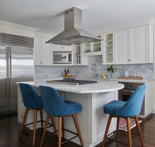 white kitchen with round kitchen island and blue bar stools