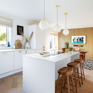white kitchen with kitchen island and bar stools and wooden veneer feature wall
