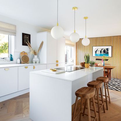 white kitchen with kitchen island and bar stools and wooden veneer feature wall