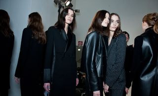 Models wearing black leather jackets with fur and gray and black striped suits, from the Costume National A/W 2015 collection.