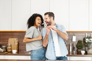 Couple singing with kitchen utensils