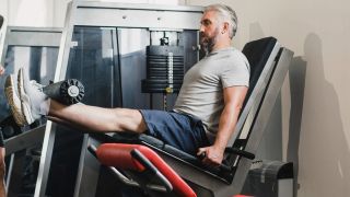 Man using leg extension weights machine in gym