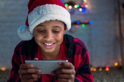 Child's fist phone - an image of a smiling boy wearing a Santa hat and using smartphone