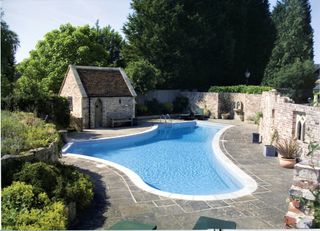 curved swimming pool in stone walled garden