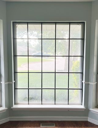 Dori Turner upgrading basic white window frames with black electrical tape to create Critall-style window frames on a budet