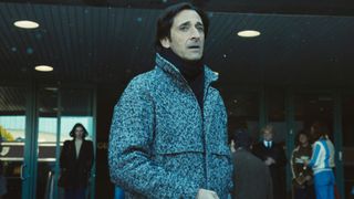 Adrien Brody as Pat Riley outside in the cold looking concerned in Winning Time season 2