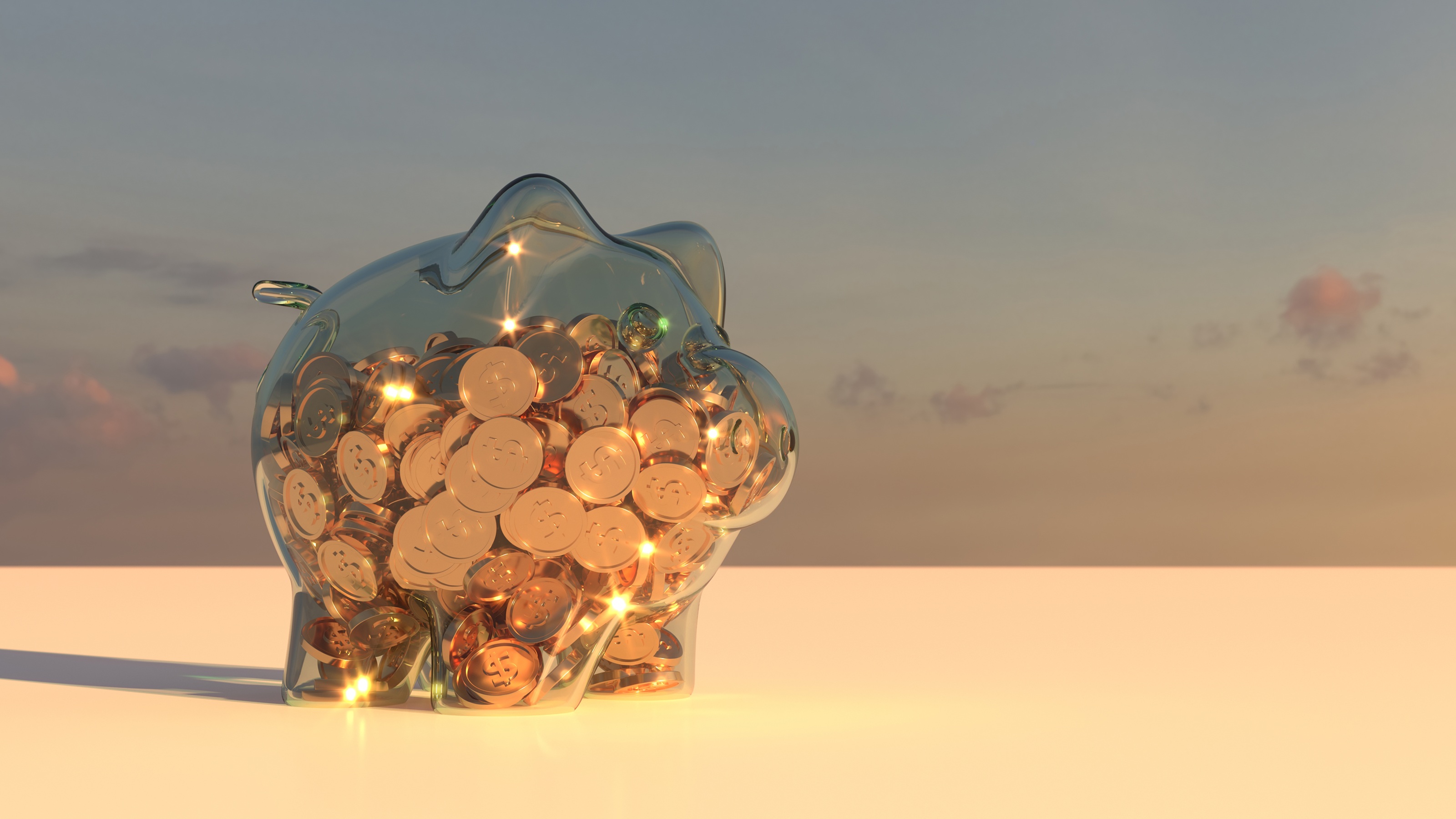 A clear piggy bank sitting outside, nearly full of gold coins.