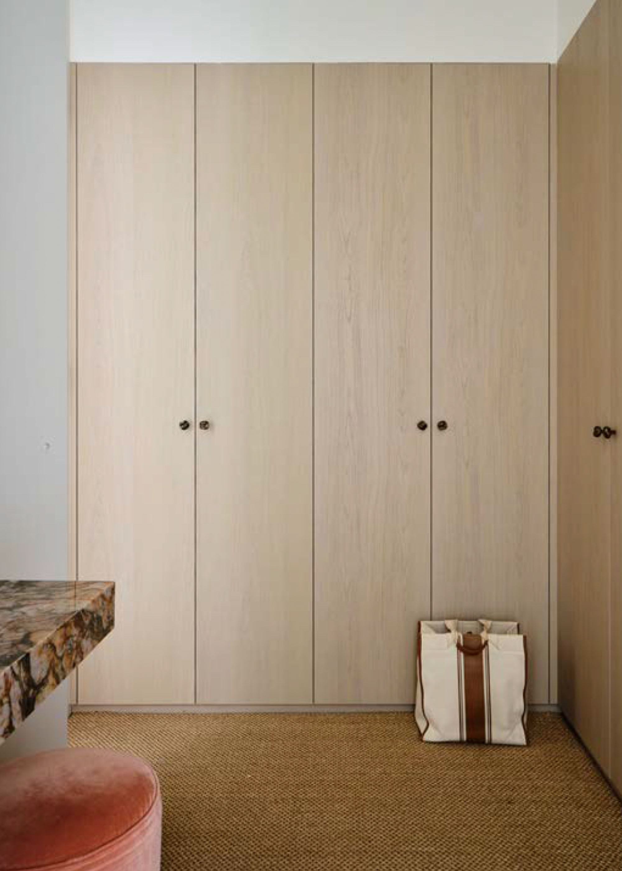 A wardrobe with wooden doors and a bag on the carpet floor