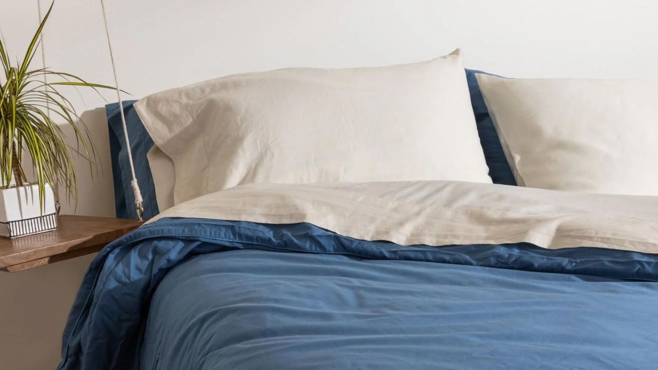 Blue and white bedding on a bed against a white wall.