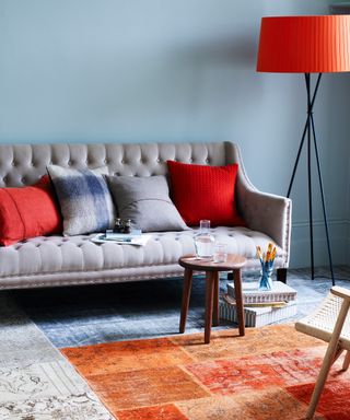 Living room with gray wall, sofa with pillows and rugs on floor