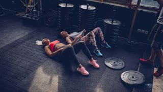 Two women rest after doing a HIIT workout with weights