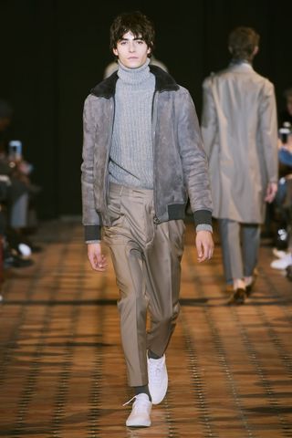 Model wearing turtle neck sweater and grey jacket
