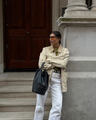 @theindiaedit wears a cream Free People canvas jacket with a pair of white jeans, studded belt, and a green T-shirt