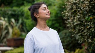 Woman deep breathing standing in a garden, practising Sophrology