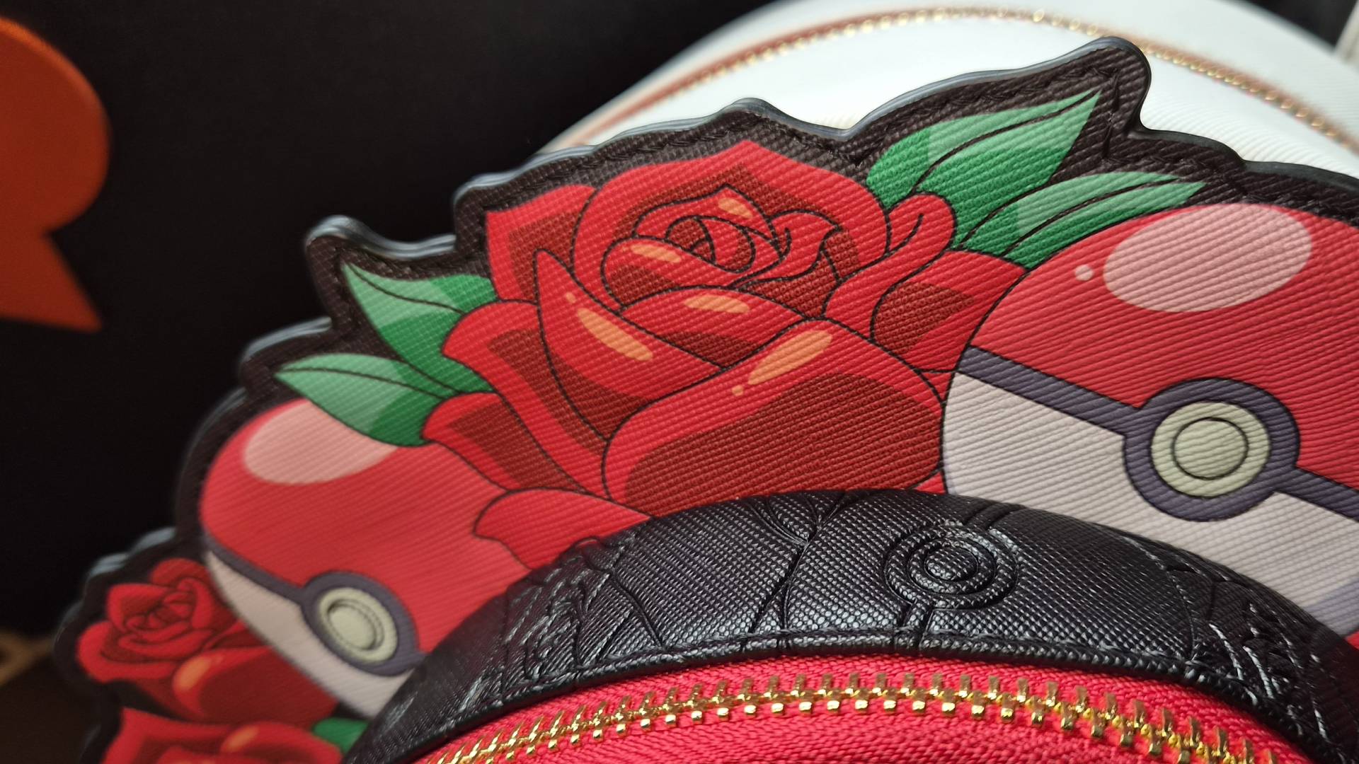 Close-up of the rose and poke ball design of the Team Rocket Cameo Mini Backpack.