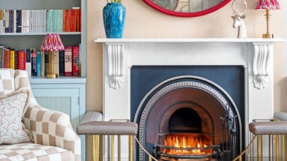 living room fireplace with mirror, vase and bookshelves