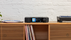 MOON 371 network amplifier on a wooden sideboard containing vinyl LPs