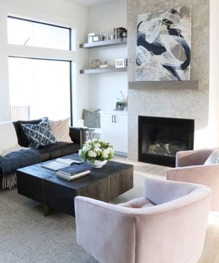 Living room with couch facing armchairs, fireplace with artwork over and neutral rug and walls