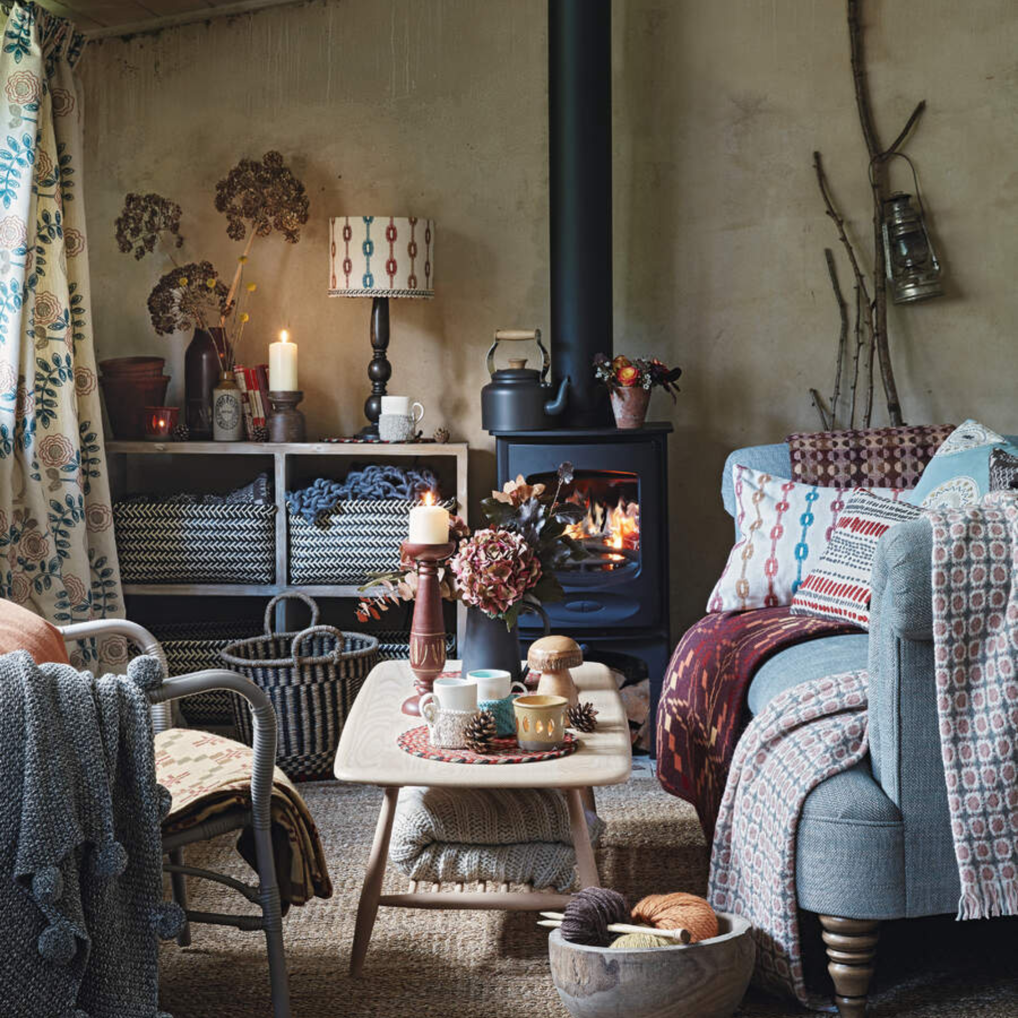 Cosy cabin living room, with a bed and woodburner stove with a lit fire.