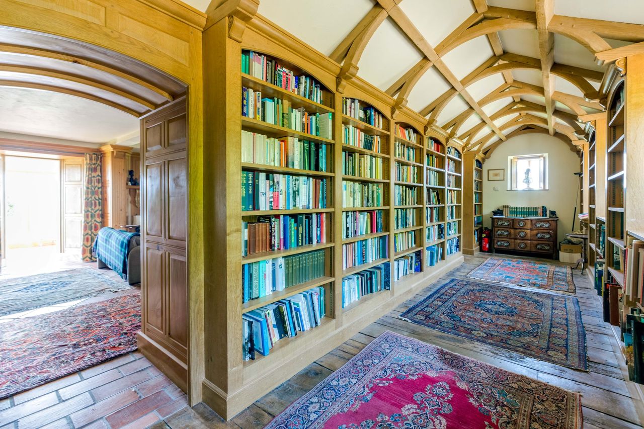 Floor-to-ceiling bookcases in the wooden library which are filled with books