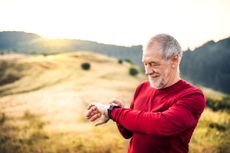 A man looks at his watch while exercising outside.