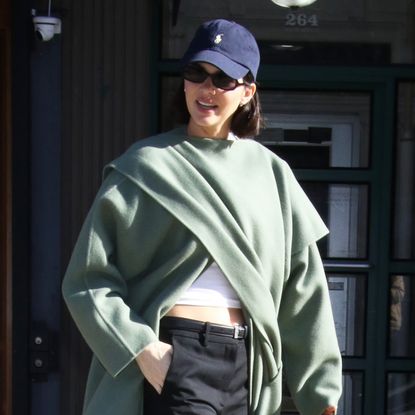 Kendall Jenner walks in New York City wearing a wrap coat and sneakers