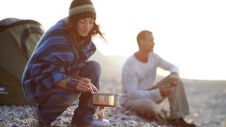 couple on beach cooking on camping stove