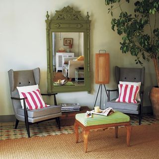 seating area with potted plant mirror and striped cushions