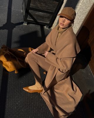 Elsa Hosk in camel coat and baseball cap.