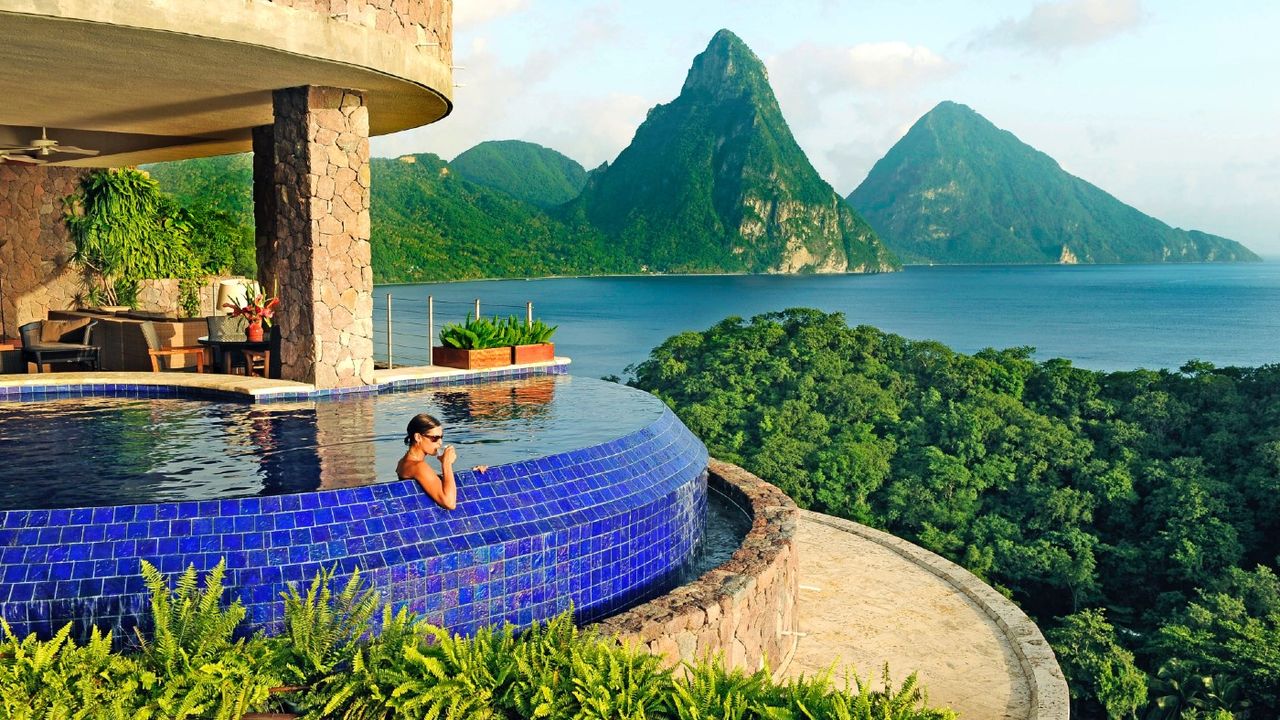 Woman in pool looking out at a mountain and body of water