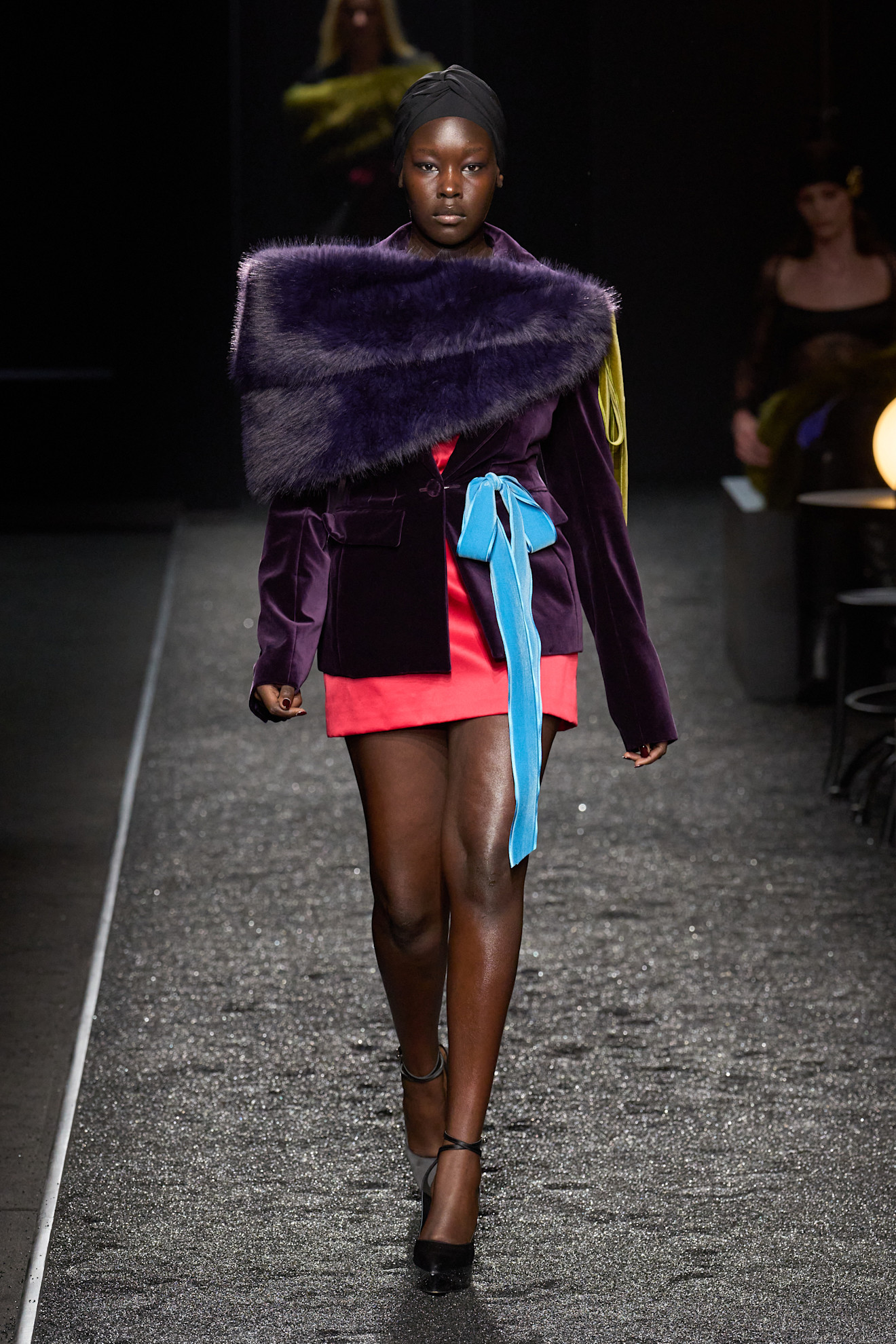 A Nina Ricci model wearing a purple shrug and blazer over a red dress