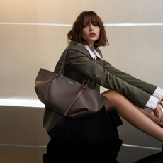 Model sat on the floor wearing a shirt and blazer with a dark brown leather Charles & Keith handbag