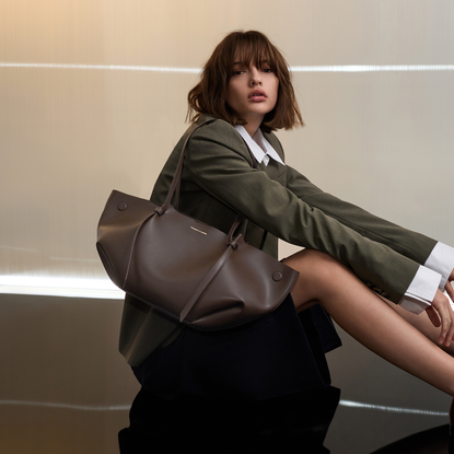Model sat on the floor wearing a shirt and blazer with a dark brown leather Charles & Keith handbag