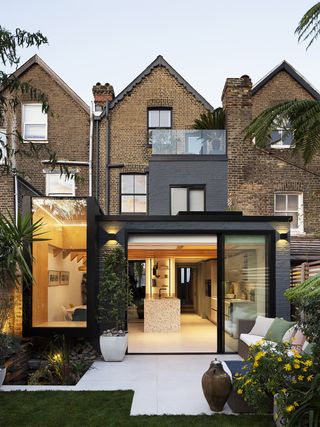 glass additions of a glass kitchen extension and a glass balcony on a modern home