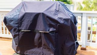 Large gas grill covered with black cover to protect from weather elements