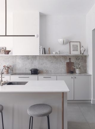A white kitchen with grey marble countertops