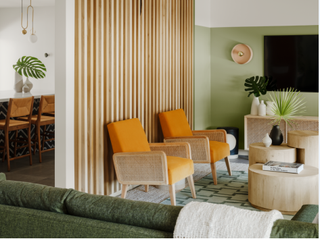 A living room with green walls and orange armchairs