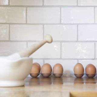 kitchen area with white wall tiles and wooden worktop with eggs.