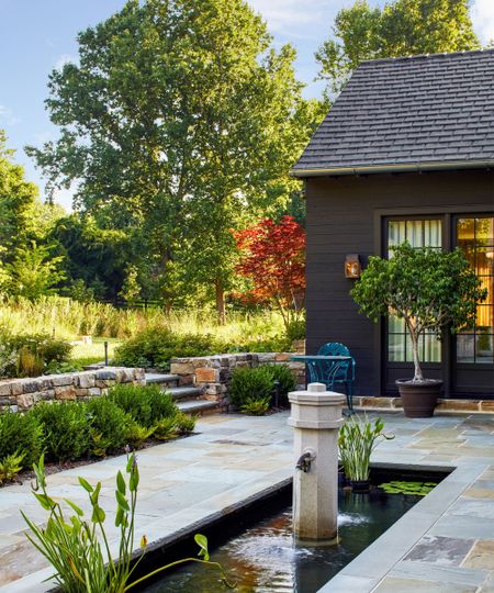 modern backyard with vintage pieces including a salvaged water fountain and metal furniture